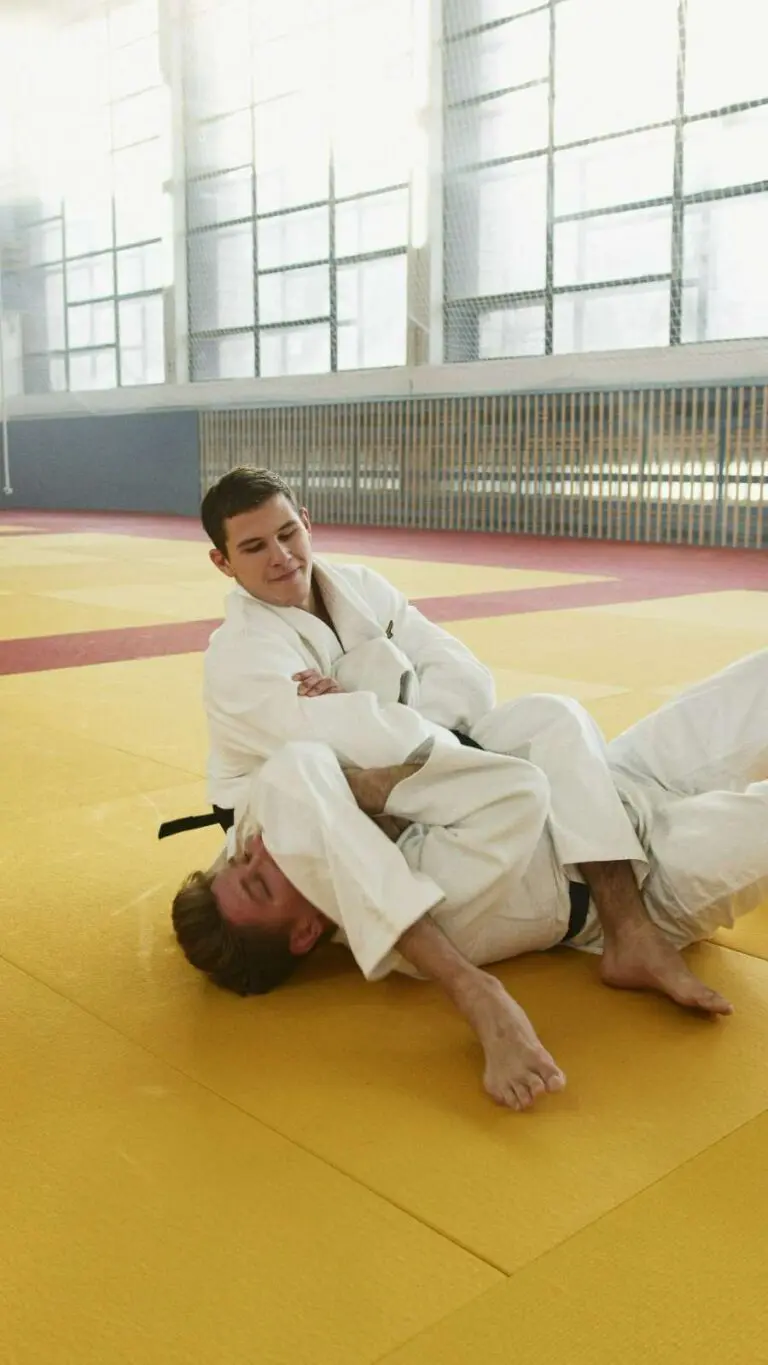 Two martial arts practitioners grappling on the mat during ground defense practice adult Taekwondo beginner progression